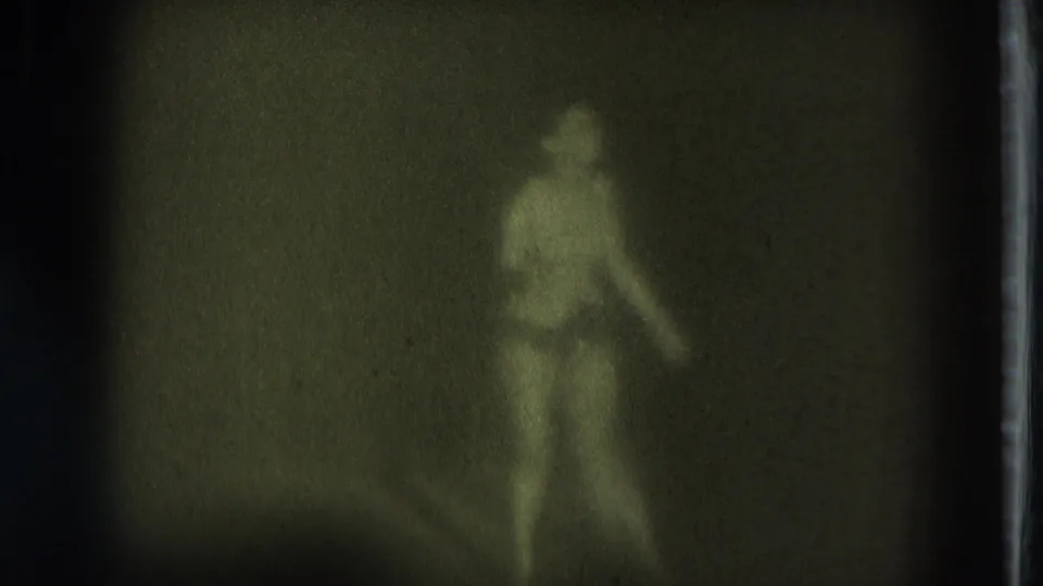 1975 San Francisco 8mm frame showing the performer turned to the side in a dim adult-stage setting with motion blur.