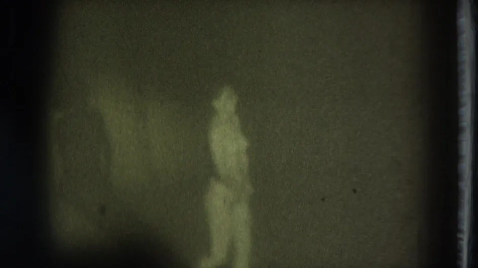 1975 San Francisco 8mm frame showing a blurred standing adult female figure in low greenish light.