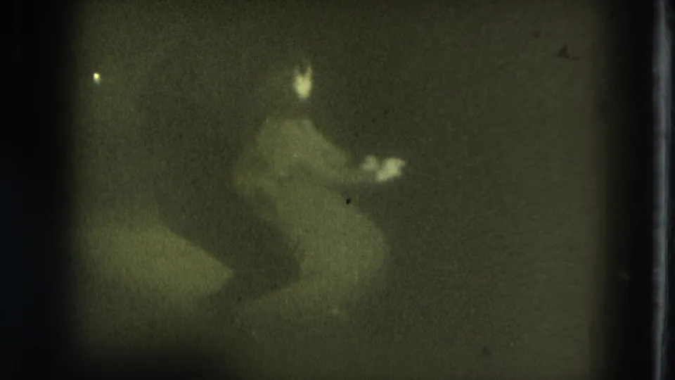 1975 San Francisco 8mm frame with an indistinct performer caught mid-motion under dim stage lighting and visible film texture.