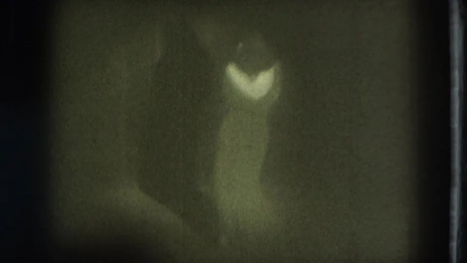 1975 San Francisco 8mm frame showing a blurred stage figure with bright costume highlights against a dark background.