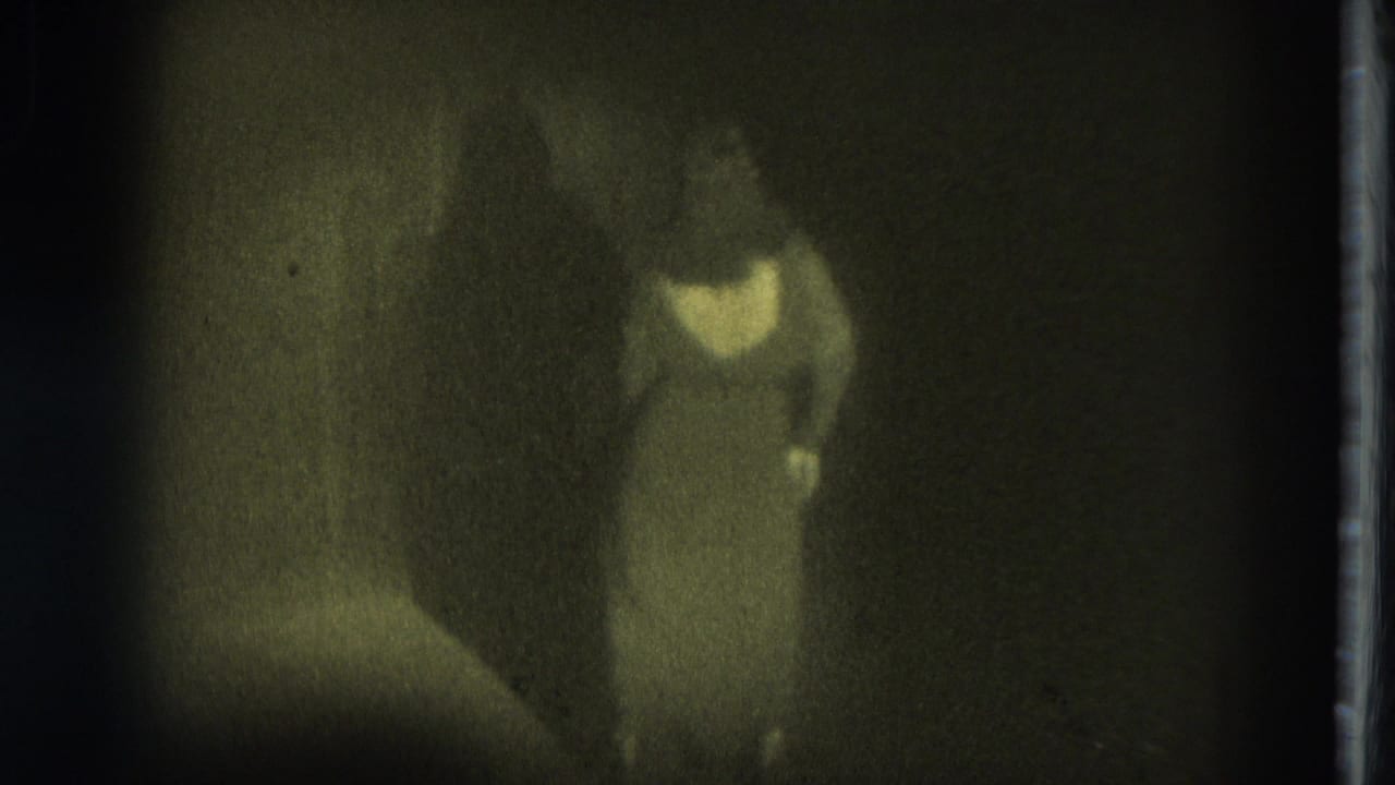 1975 San Francisco 8mm frame showing a blurred performer in light clothing under dim spotlighting.