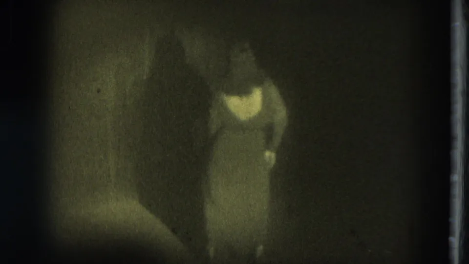 1975 San Francisco 8mm frame showing a blurred performer in light clothing under dim spotlighting.