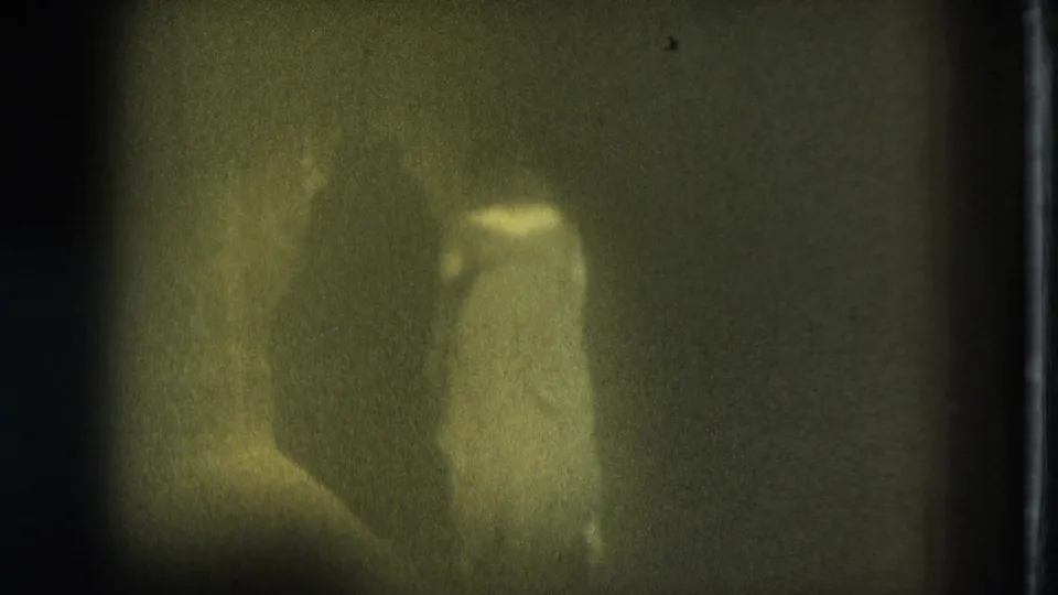 Adult woman in underwear appears in a dim, green-tinted 1975 San Francisco 8mm frame.