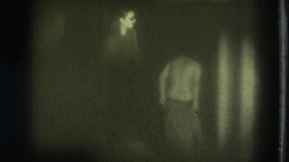 Adult woman appears from behind in a dark, grainy 1975 San Francisco home-movie frame.