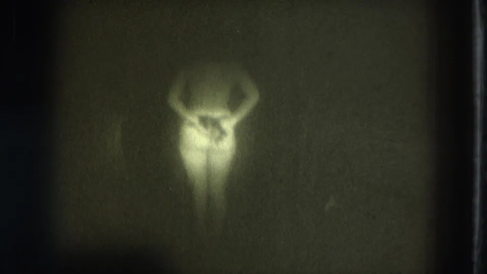 1975 San Francisco 8mm frame with a woman in soft silhouette, arms raised, seen through grain and underexposure.