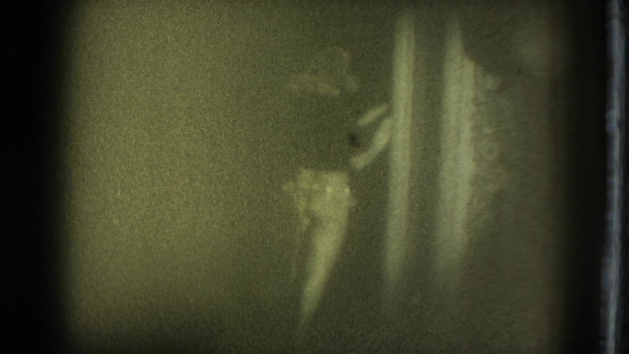 Blurry performer on a dim stage near a vertical curtain edge.