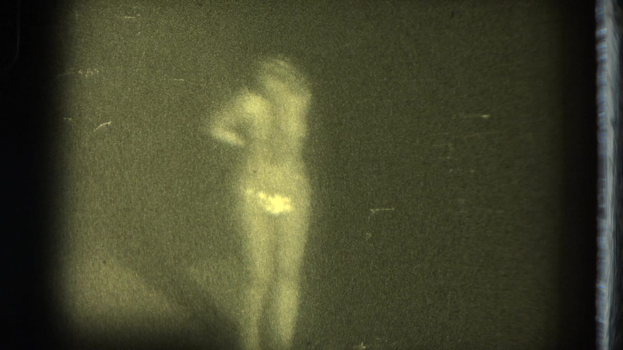 The woman appears turned partly away from the camera, holding a pose in soft-focus 1975 San Francisco home-movie footage.