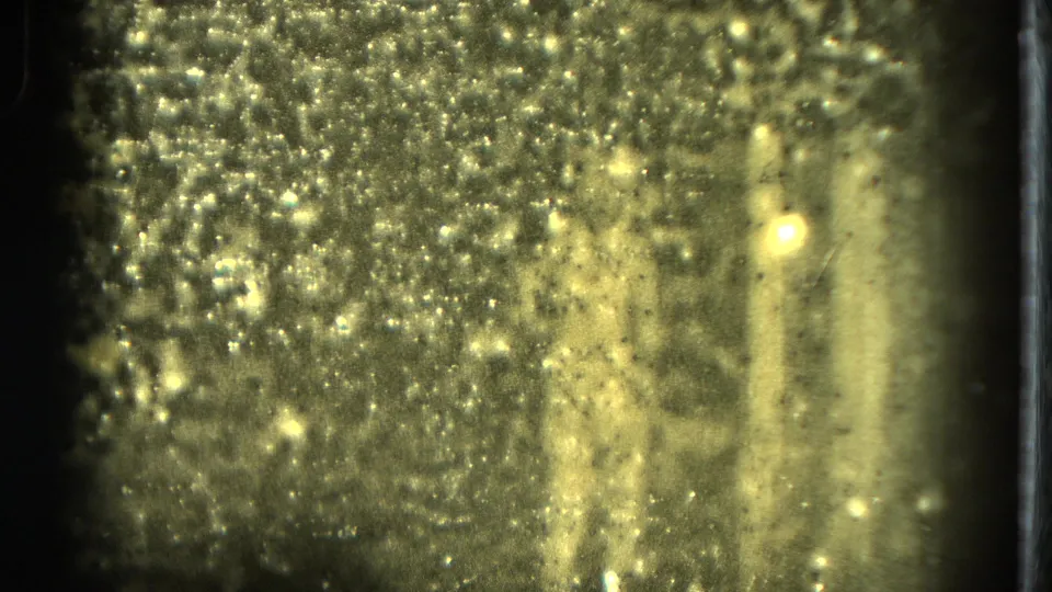 A heavily textured 8mm frame shows the nude stage performer partly obscured by glare, grain, and low-light exposure.