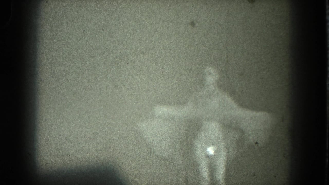 1975 8mm San Francisco home-movie frame of a woman in a pale dress posed with arms outstretched in soft silhouette.