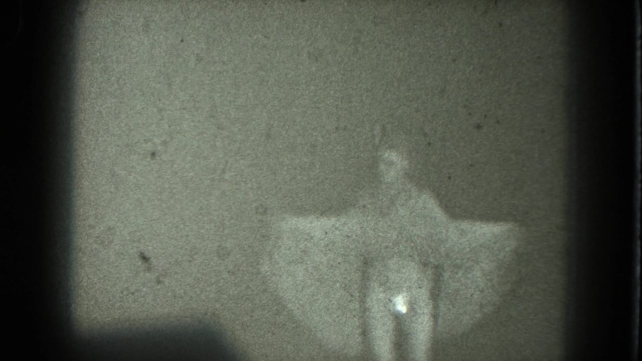 1975 8mm San Francisco frame showing a woman in a pale dress turning or posing with one arm extended.