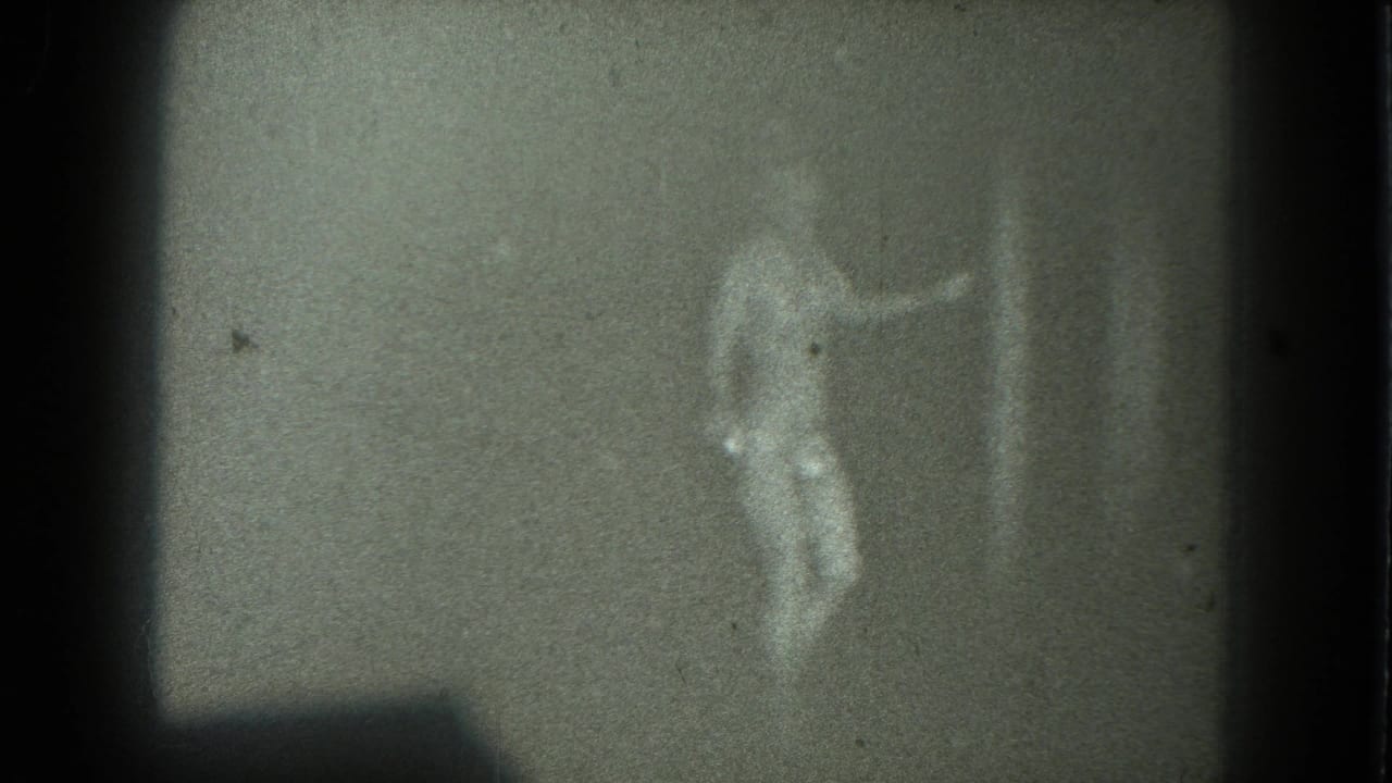 Blurred adult woman dancing in a reflective outfit against a dark background.
