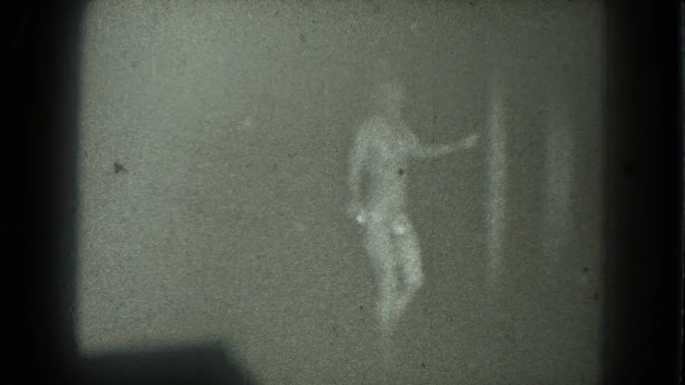 1975 San Francisco 8mm frame of an adult woman in a shimmering outfit raising one arm while dancing in soft focus.