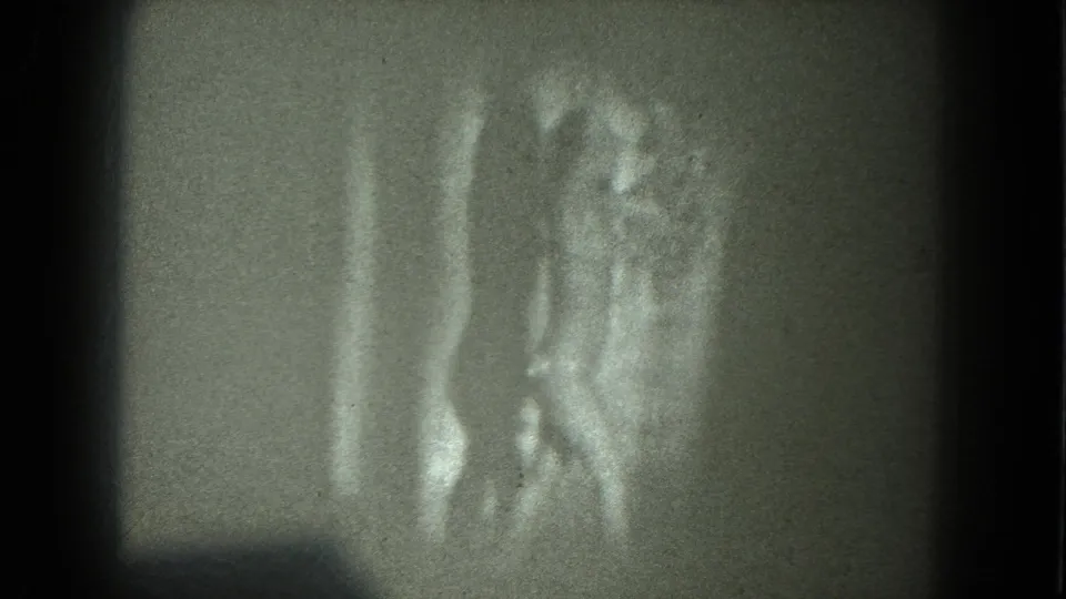 1975 San Francisco 8mm frame showing an adult woman in revealing reflective clothing with arms lifted in a dance pose.