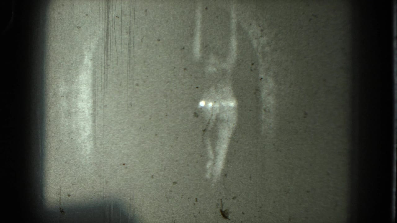 1975 San Francisco 8mm frame showing an indistinct adult dancer with arms raised, bright highlights, and heavy film grain.