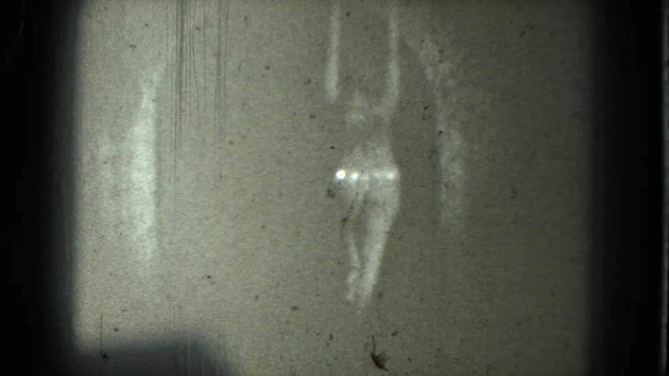 1975 San Francisco 8mm frame showing an indistinct adult dancer with arms raised, bright highlights, and heavy film grain.