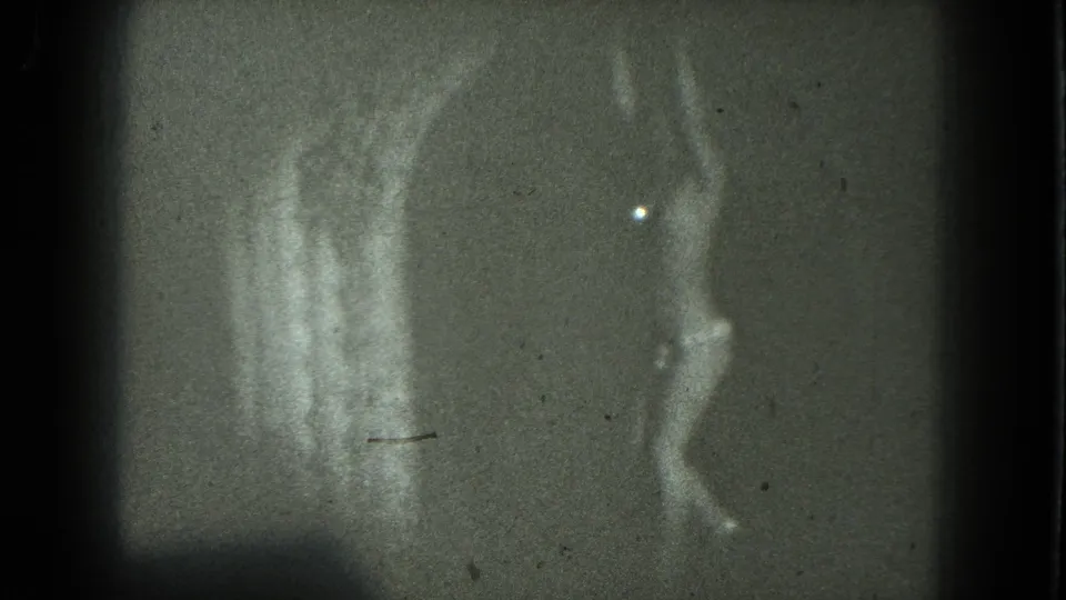 1975 San Francisco 8mm frame with an adult dancer at right, pale vertical smears, dark edges, and visible film wear.
