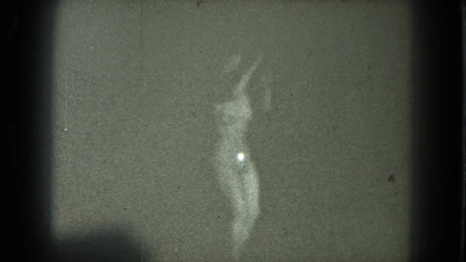 1975 San Francisco 8mm frame of a woman dancing, with one arm raised and a bright highlight on her lower torso.