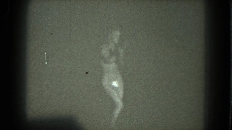 1975 San Francisco 8mm frame showing the dancer in motion, with visible scratches, grain, and a bright lower-body reflection.