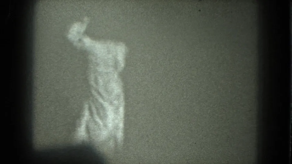 Adult woman in a light robe appears to dance indoors in grainy 1975 8mm home-movie footage from San Francisco metadata.