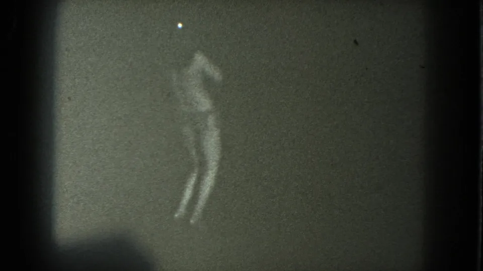 A silhouetted performer appears to lean or sway with one arm raised in a grainy 8mm frame from the San Francisco clip.