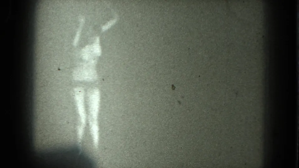 1975 San Francisco 8mm frame showing a woman in minimal clothing or nude with one arm raised during a dance movement.