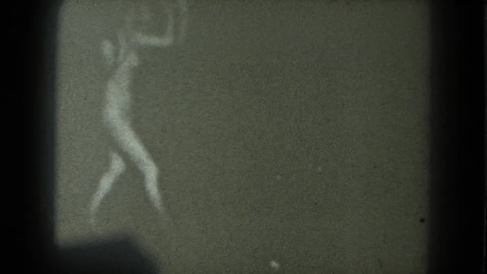A blurred adult woman appears to dance in a dark, grainy 1975 8mm home-movie frame from San Francisco metadata.