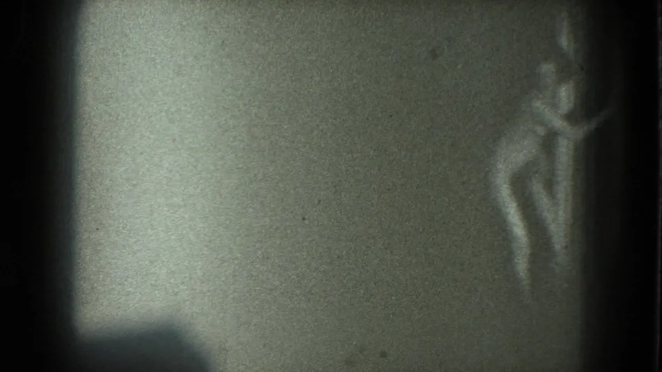 The figure stands near the right side of the 8mm frame, softened by low light, film grain, and motion blur.