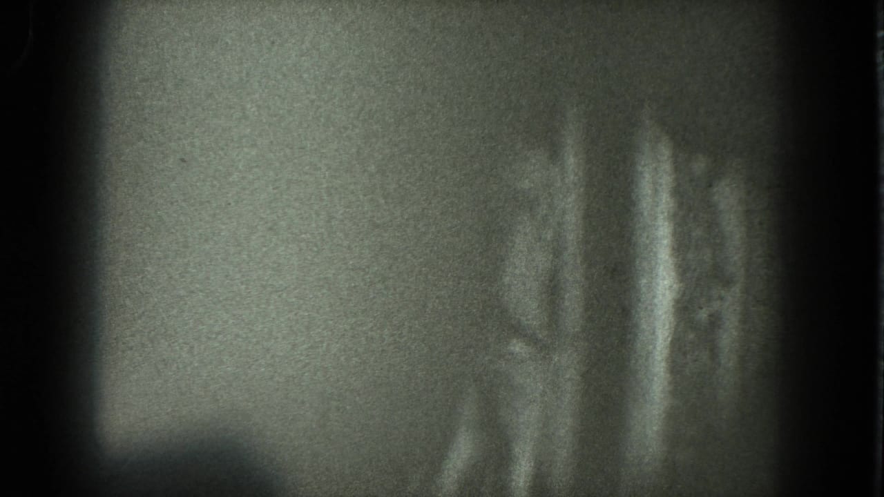 Soft, grainy view of a woman standing or dancing in a dark room.
