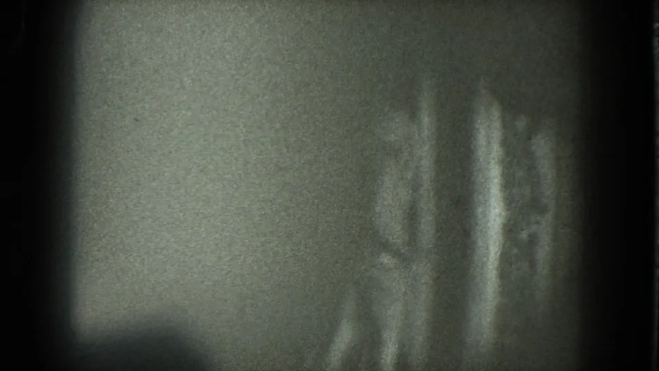1975 San Francisco 8mm frame showing a woman in soft focus against a dim background, her body partly turned as she dances.