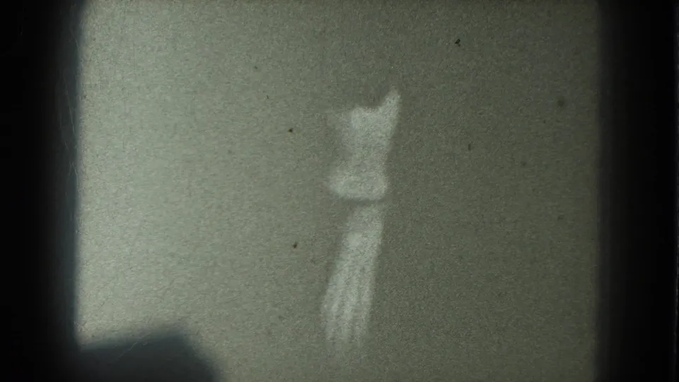 1975 8mm San Francisco club footage appears to show a woman dancing from behind in dim light, with strong grain and soft focus.