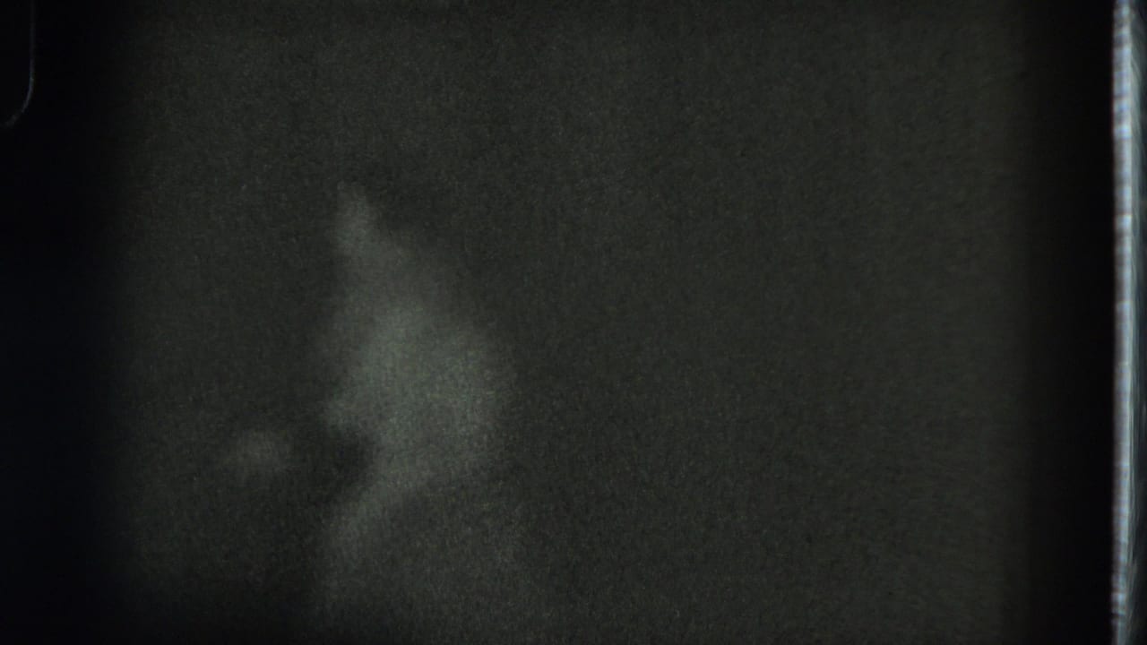 Dancer turns in profile, partly blurred by low light and film grain.