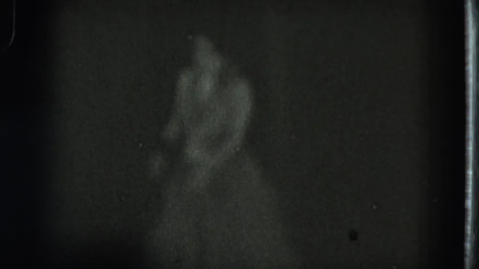 The dancer appears sideways with a bent arm and skirt visible, recorded in low-light 1975 San Francisco 8mm footage.