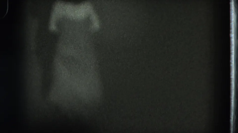 A final 8mm frame shows the performer centered in a pool of light, with the dress shape visible but facial detail obscured.
