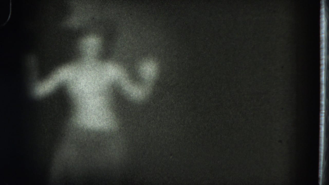 Adult woman in light clothing with both arms lifted in a dark frame.