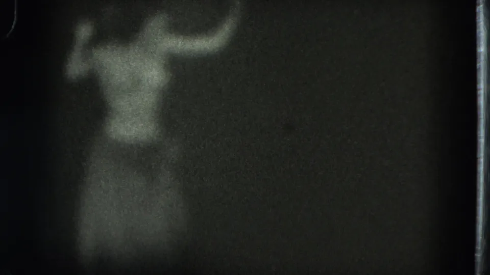Final 8mm frame shows the adult woman as a soft silhouette with raised arms against a nearly black interior.