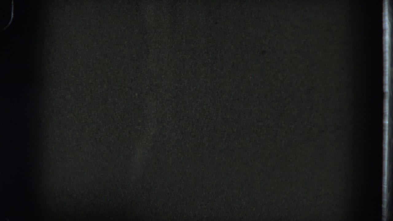 Low-exposure 1975 8mm frame from San Francisco with mostly dark interior detail and visible film border.