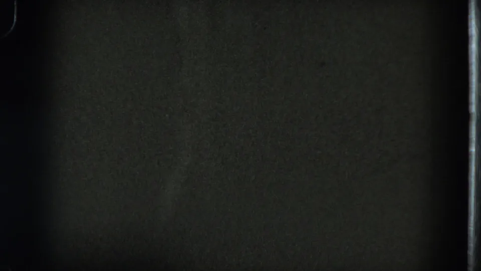 Low-exposure 1975 8mm frame from San Francisco with mostly dark interior detail and visible film border.