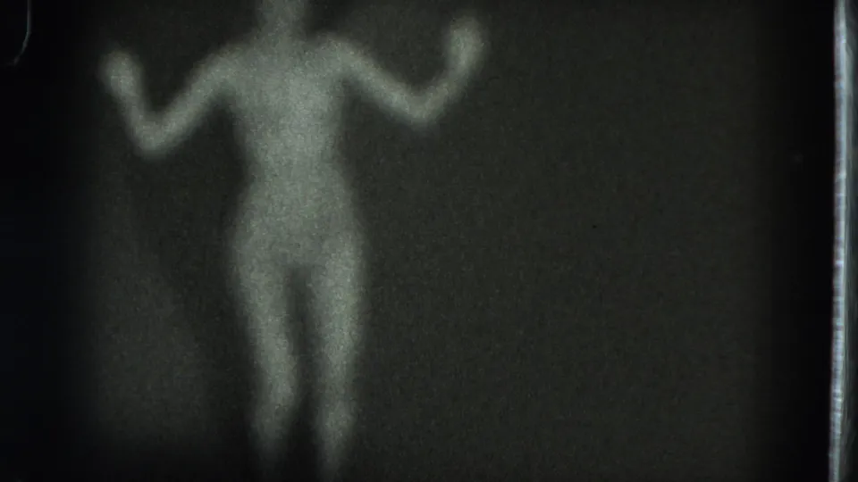 Soft-focus 1975 8mm frame from San Francisco showing a nude adult woman facing camera during a dance movement.