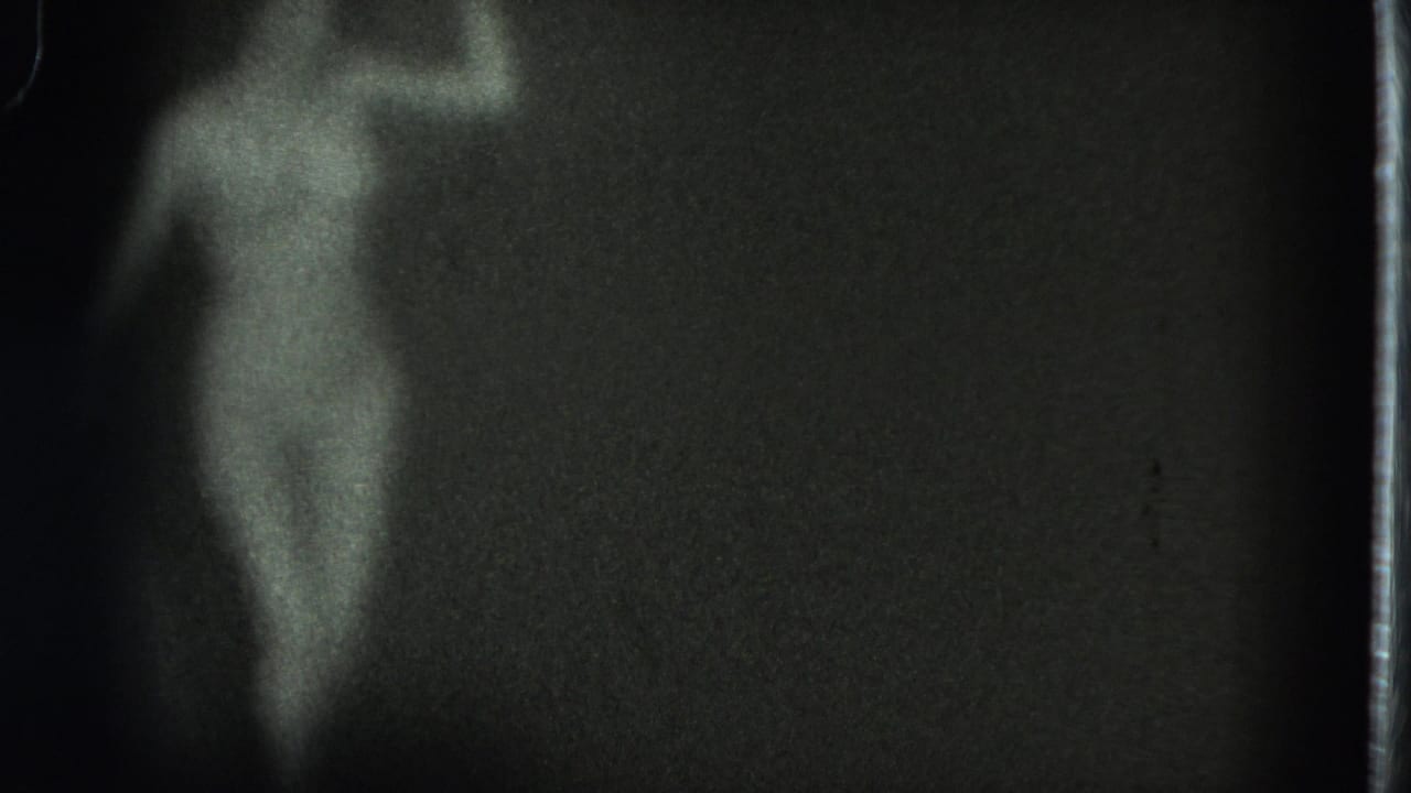 Performer seen in profile near the edge of a dark stage frame.