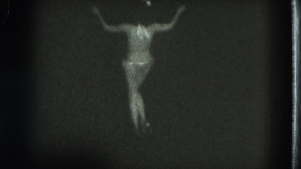 1975 San Francisco 8mm frame showing the dancer posing from behind with arms raised and one leg bent.
