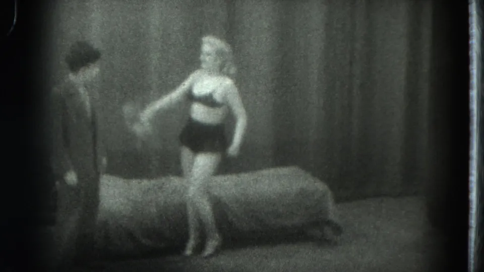 1975 8mm San Francisco stage frame showing a woman in a black top and shorts waving a scarf near a man.