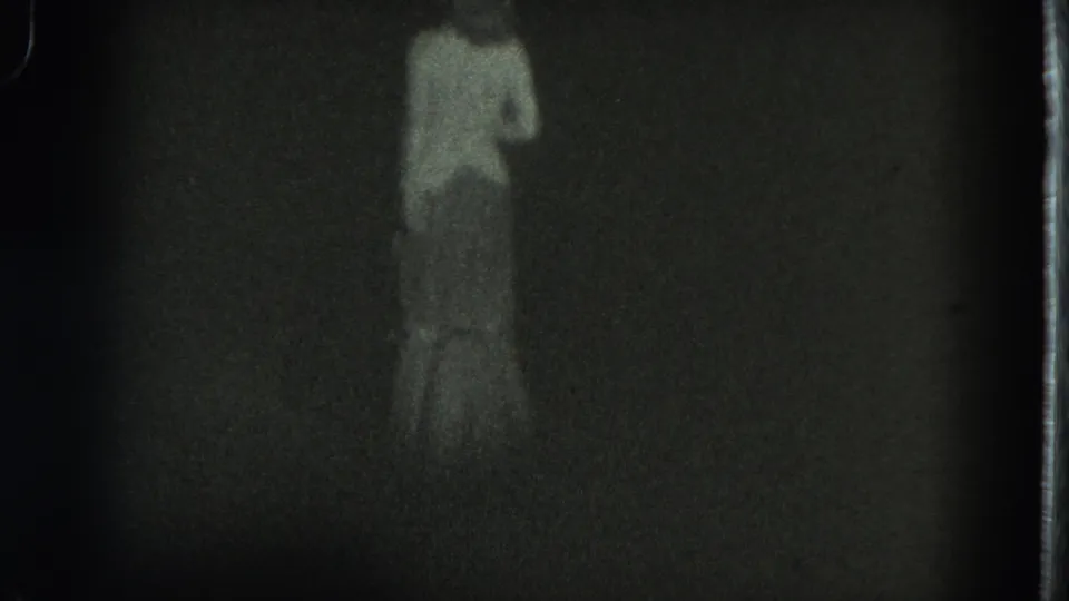 1975 San Francisco night frame with a distant woman in a long dress, rendered in soft focus and heavy 8mm grain.