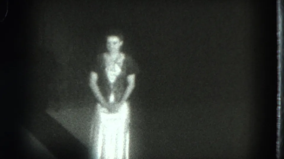 A woman faces the camera in a bright white skirt, her face softened by grain and exposure.