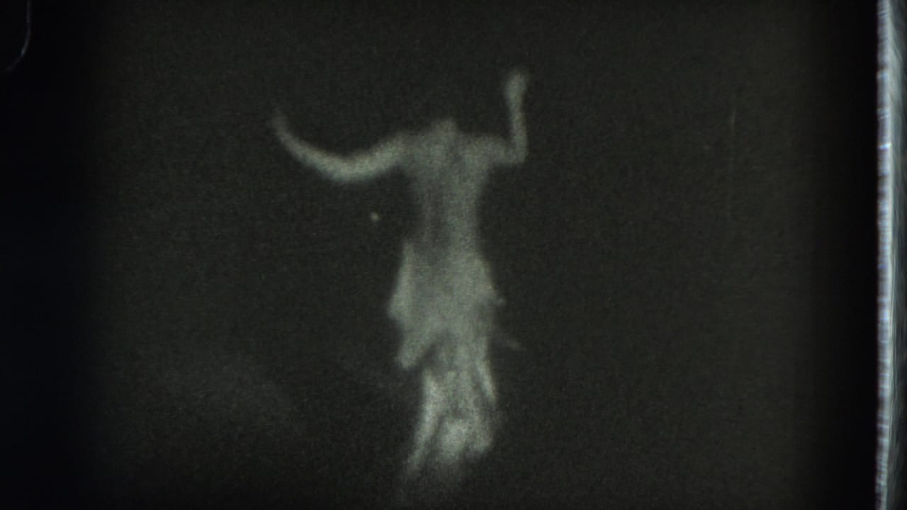 Blurred dancer with both arms lifted against a black background.