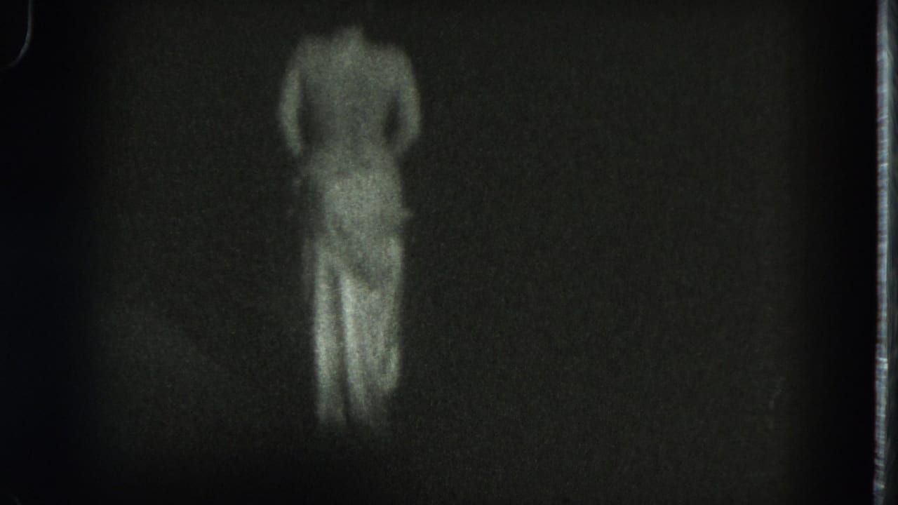The adult dancer is centered with back to camera, skirt visible, in dim black-and-white 8mm footage from the San Francisco clip.