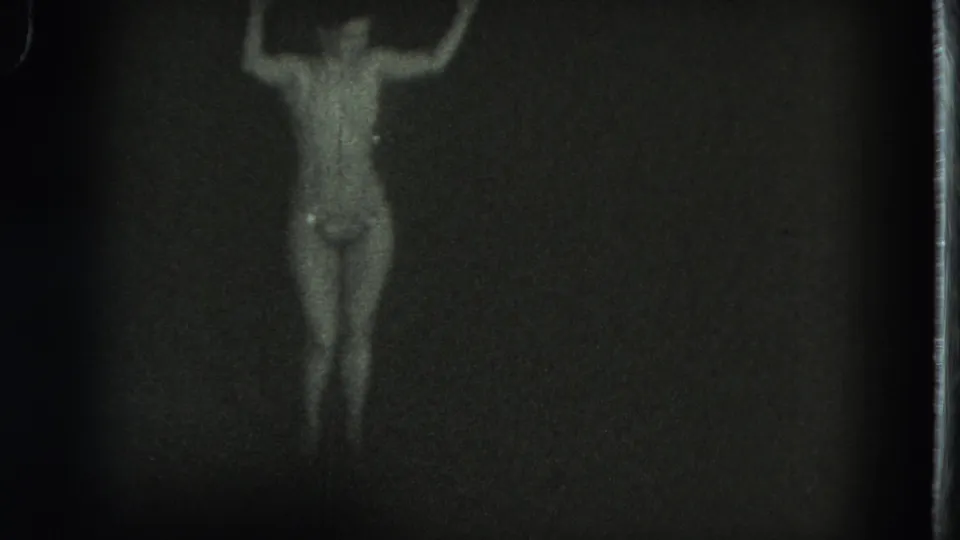 1975 San Francisco 8mm frame showing the dancer slightly turned, one arm higher, with the figure emerging from a dark background.