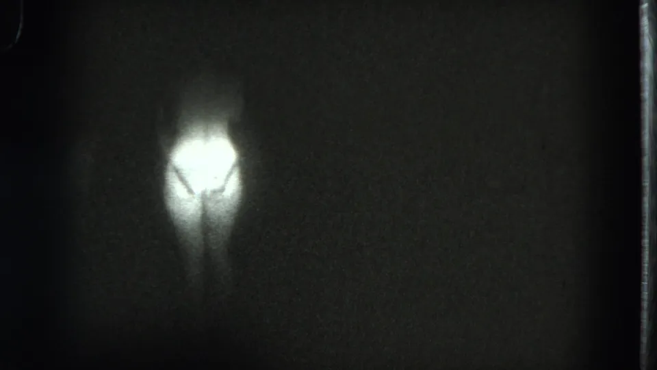 1975 San Francisco 8mm frame where the performer is mostly obscured by darkness and a blown spotlight on the bikini area.