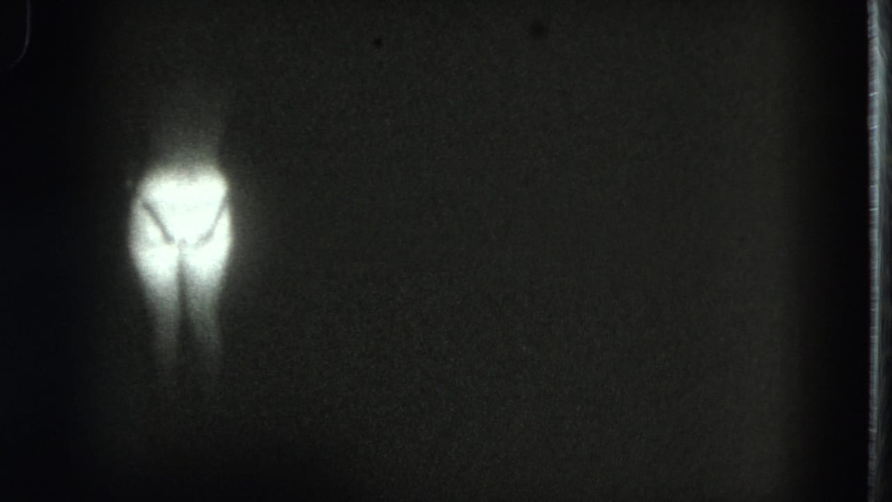 Small bright silhouette near the left side of a dark film frame.