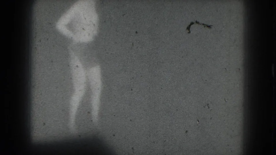 1975 San Francisco 8mm frame showing a distant silhouetted performer with raised arms, softened by grain, dust, and low contrast.