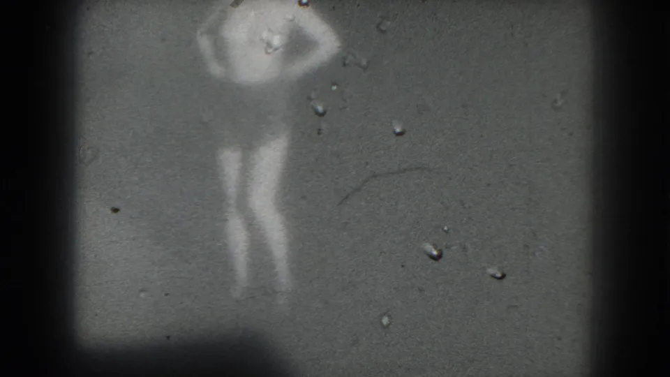 1975 San Francisco 8mm frame with a blurred stage performer, one arm bent near the head, surrounded by dust marks and dark borders.